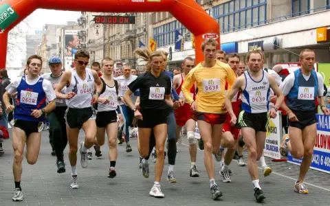 Löpare i en maratonlopp, många med nummerbrickor. En kvinna springer i mitten.
