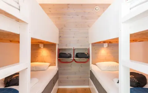Två våningssängar i en mysig stuga, perfekt för camping i Åre. Sängkläder och sovsäckar redo för äventyr.