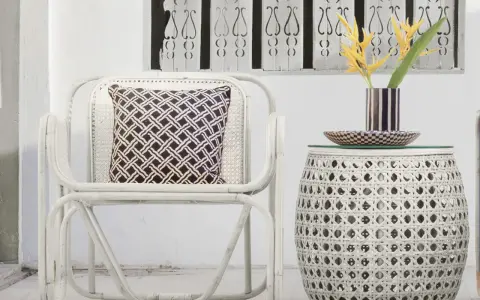 Sillón y mesa auxiliar de mimbre blanco, con cojín estampado y flores amarillas. Ideas de colores para pintar mimbre.