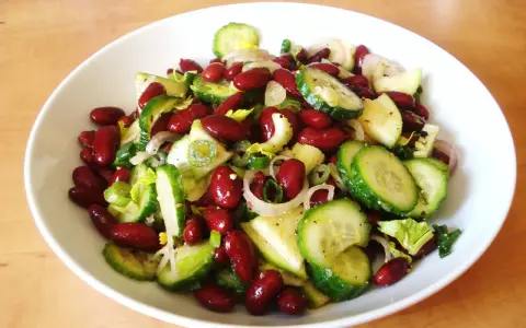 Salade colorée de haricots rouges, concombre, oignon rouge et céleri, prête à être dégustée.