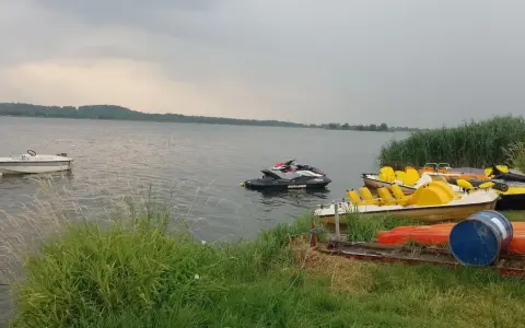 Na jeziorze Paczkowskim pływa motorówka i skutery wodne. Na brzegu czekają rowery wodne i kajaki.