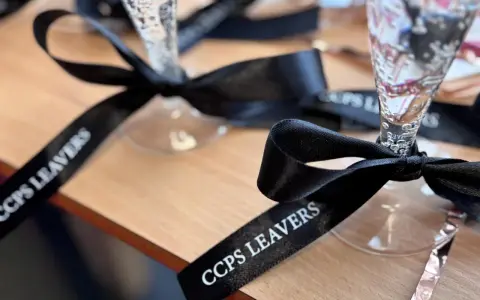 Copas de champán con lazos personalizados negros con el texto "CCPS LEAVERS" para una celebración especial.