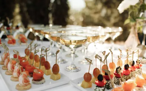 Elegantes aperitivos para bodas: camarones, salmón, queso y frutas en brochetas, junto a copas de champán.