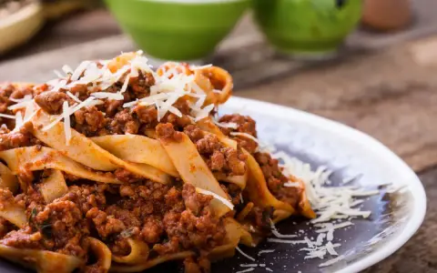 Pappardelle z bogatym sosem bolognese, idealne pytanie: jakie mięso do spaghetti? Posypane parmezanem.