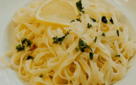 En portion krämig citronpasta med färsk persilja och en citronskiva. Perfekt till ett glas vitt vin.