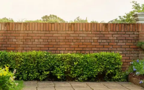 Eine Ziegelmauer im Garten, umgeben von üppigem Grün und blühenden Pflanzen. Tolle Ideen für Gartenmauern!