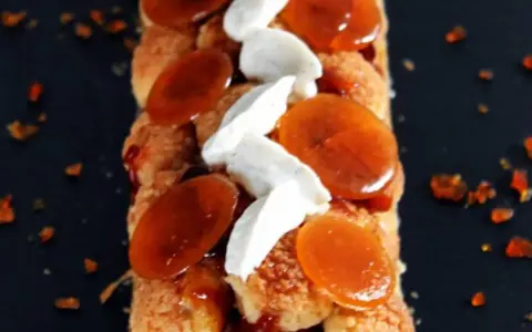 Bûche Saint Honoré gourmande, garnie de choux craquelins, crème onctueuse et éclats de caramel ambré. Un délice visuel et gustatif.