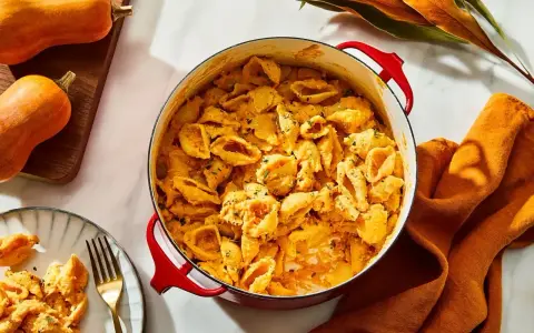 Pyszny makaron z dynią w kremowym sosie, idealny pomysł na co na kolacje. Obok leżą dynie i pomarańczowa serwetka.