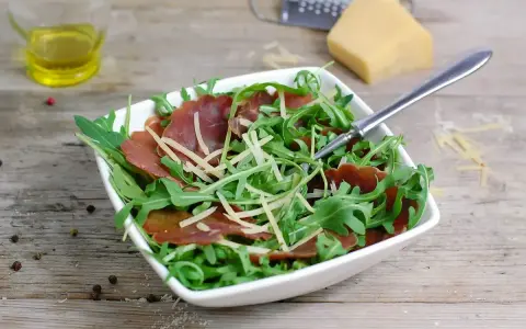Insalata fresca con bresaola rucola e grana, condita con olio d'oliva e pepe.