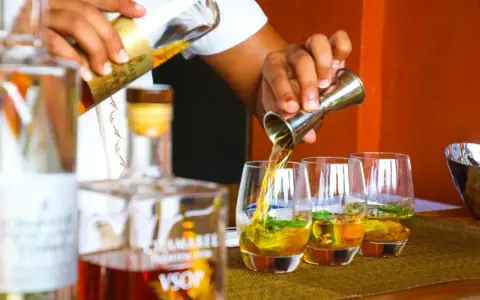 Barman nalewa cachacę do szklanek z lodem i miętą. To popularny brazylijski alkohol.
