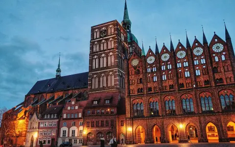 Abendstimmung auf dem Marktplatz der **Stralsund Altstadt**. Backsteingotik dominiert, mit dem Rathaus und der Marienkirche im Dämmerlicht.