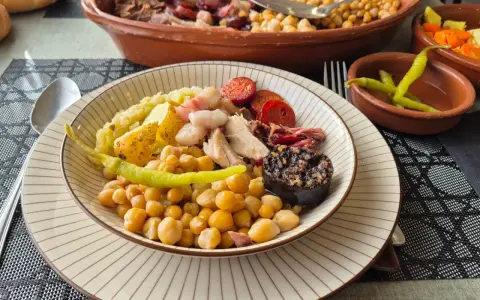 Plato de cocido con garbanzos, patatas, chorizo, morcilla y pimientos.