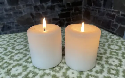 Two white candles glow softly, their flames flickering. This peaceful scene evokes the second Sunday of Advent theme of hope and preparation.