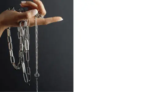 Mano con anelli che mostra diverse collane Pesavento, con maglie lucide e un design moderno. Scopri i prezzi.