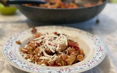 Plato de pasta alla norma con fusilli, berenjena, tomate y queso rallado, listo para disfrutar.