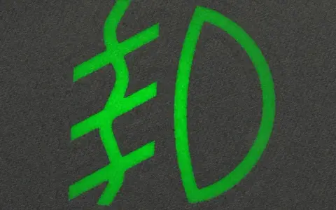 Zielony symbol świateł mijania na ciemnym tle.