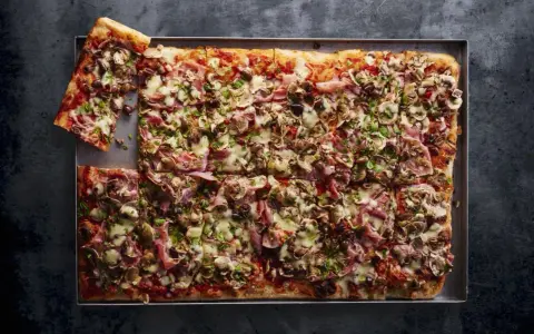 Pyszna pizza domowa przepis na blachę z szynką, pieczarkami i oliwkami. Idealna na rodzinne spotkanie.