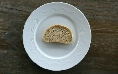 Jedna kromka chleba na białym talerzu. Zastanawiasz się, ile g ma kromka chleba?