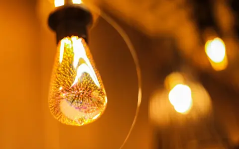 Une ampoule décorative aux filaments lumineux, projetant une lumière chaude et dorée. L'étiquette ampoule est subtilement intégrée dans le design.