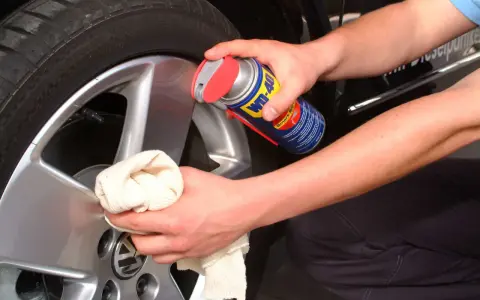 Person reinigt Felgen mit WD-40 und Tuch. Ein Hausmittel für glänzende Felgen.