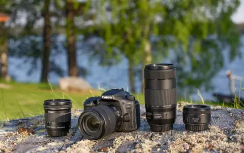 Aparat Canon EOS 90D z obiektywami 10-18mm, 70-300mm i 50mm na kamieniu nad jeziorem.