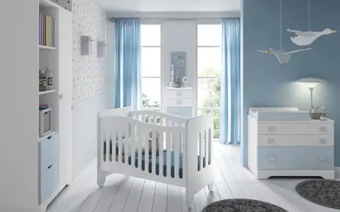 Habitación de bebé con cuna blanca, cómoda azul y estantería. Los colores para habitación de bebé son serenos, con predominio del azul y blanco.