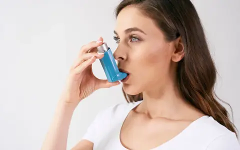 Frau mit Inhalator, der bei Asthma hilft. Hohe Luftfeuchtigkeit kann Symptome verschlimmern.