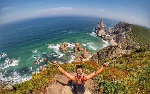 Frau genießt die atemberaubende Lissabon Natur am Cabo da Roca. Türkises Meer, Felsen und üppige Vegetation.