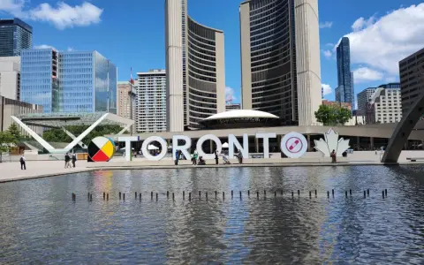 Toronto co zobaczyć: wielki napis TORONTO przed ratuszem miejskim, z fontanną i nowoczesnymi budynkami w tle.