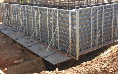 Casse edili metalliche montate per gettare una fondazione in cemento armato, con armature metalliche visibili in alto.