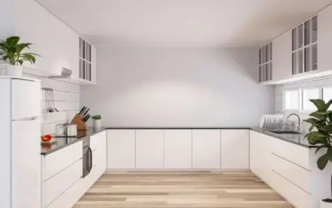Cucina moderna con mobili bianchi e pavimento in legno. Idee per come riempire una parete vuota in cucina con mensole o quadri.