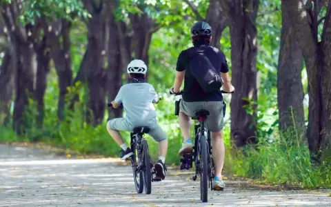 Dwie osoby na rowerach jadą alejką wśród drzew. Idealne miejsce na odkrywanie tras rowerowych Rzeszów.