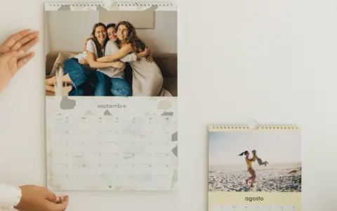 Un calendario personalizado con fotos de amigos y familia. El mes de septiembre muestra a tres amigas abrazándose, y agosto a una madre jugando con su hijo en la playa.
