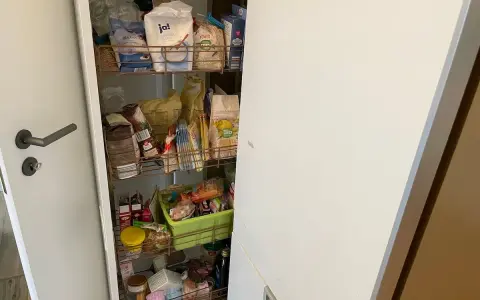 Ein offener Apothekerschrank mit vielen Lebensmitteln. Hier wird gezeigt, wie man einen Apothekerschrank organisieren kann, um Platz zu sparen.