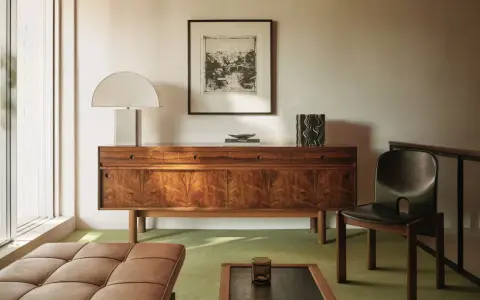 Elegante aparador de madera con **mid century decoracion**, lámpara de diseño, cuadro y silla de cuero.