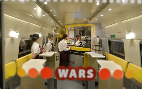 Wnętrze pociągu z personelem obsługującym bar. Widoczny napis "WARS".