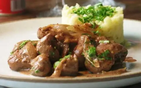 Une assiette de fricassée de rognons de veau, tendres et savoureux, accompagnés d'une purée de pommes de terre onctueuse et garnie de persil frais.