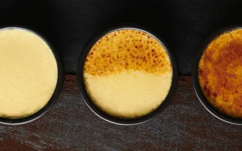 Trois ramequins de crème brûlée, de l'origine à la perfection caramélisée. La texture onctueuse et les grains de vanille sont visibles.