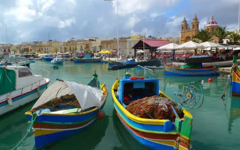 Kolorowe łodzie rybackie w porcie na Malcie, gdzie można poczuć klimat i zobaczyć, jak wygląda malta waluta w codziennym życiu.