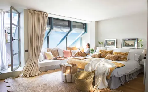 Habitación acogedora con cama grande, cojines coloridos y una zona de lectura junto a la ventana. Ideas para decorar habitacion con estilo natural.