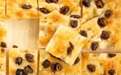 Goldbraune Focaccia mit Oliven, perfekt nach dem original focaccia rezept. Ein Stück ist leicht angehoben.