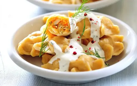 Pyszne pierogi z farszem, polane sosem śmietanowym i posypane koperkiem i pieprzem. Idealne co na uroczysty obiad.