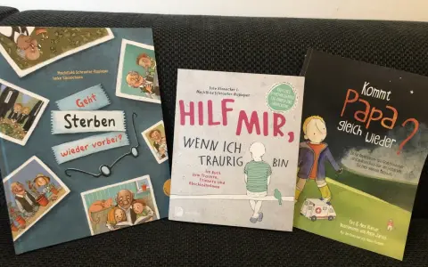 Drei Kinderbücher zum Thema Trauer und Verlust. Ein Kind sieht seinen verstorbenen Opa auf einem Bild.