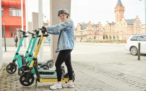 Tjej med hjälm redo att köra elsparkcykel. Tänk på elsparkcykel regler för en trygg resa.