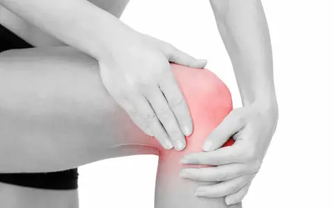 En person håller om ett knä som lyser rött, vilket indikerar smärta. Här sitter benhinnorna, som kan drabbas av inflammation.
