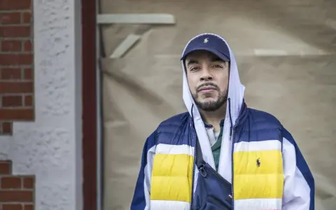 Man i hip hop style med keps och färgglad jacka.