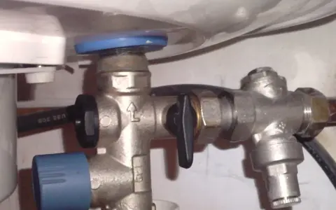 Un réducteur de pression, comme ce dispositif métallique avec une poignée noire, sert à réguler la pression de l'eau dans une installation.