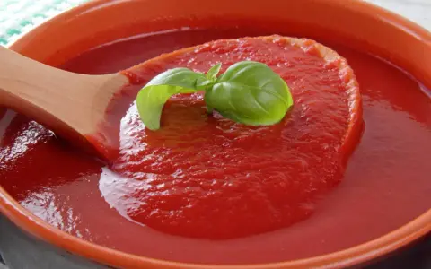 Gęsty, domowy ketchup w ceramicznej misie, nabierany drewnianą łyżką. Idealny przepis na ketchup z bazylią.