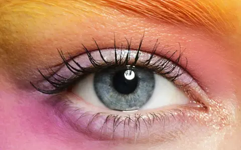Occhio azzurro con ombretto rosa e arancione, ciglia lunghe e folte. Un esempio di come truccare gli occhi piccoli per farli sembrare più grandi.