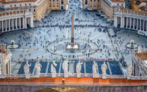 Vue aérienne de la **place du Vatican**, avec son obélisque central, ses fontaines et une foule de visiteurs.